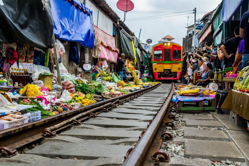 Capture the excitement of Mae Klong Market in Thailand with a train passing through vibrant stalls filled with fresh produce.