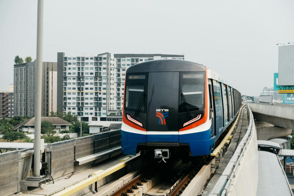 Front view of the BTS Skytrain in Bangkok on elevated tracks with cityscape background.