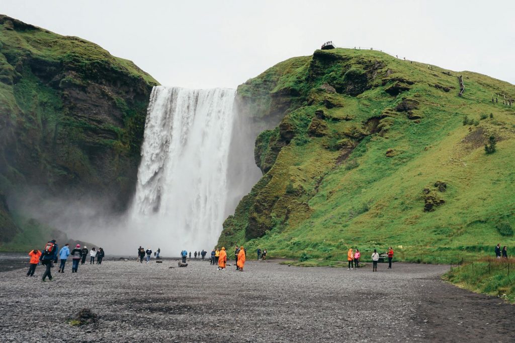 Stunning view of Skogafoss waterfall in Iceland with tourists exploring the natural beauty.