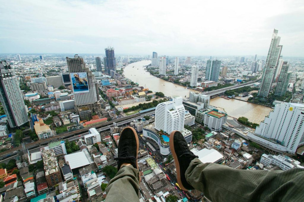 A thrilling cityscape of Bangkok with a bird's-eye view over the river and shoes in the foreground.