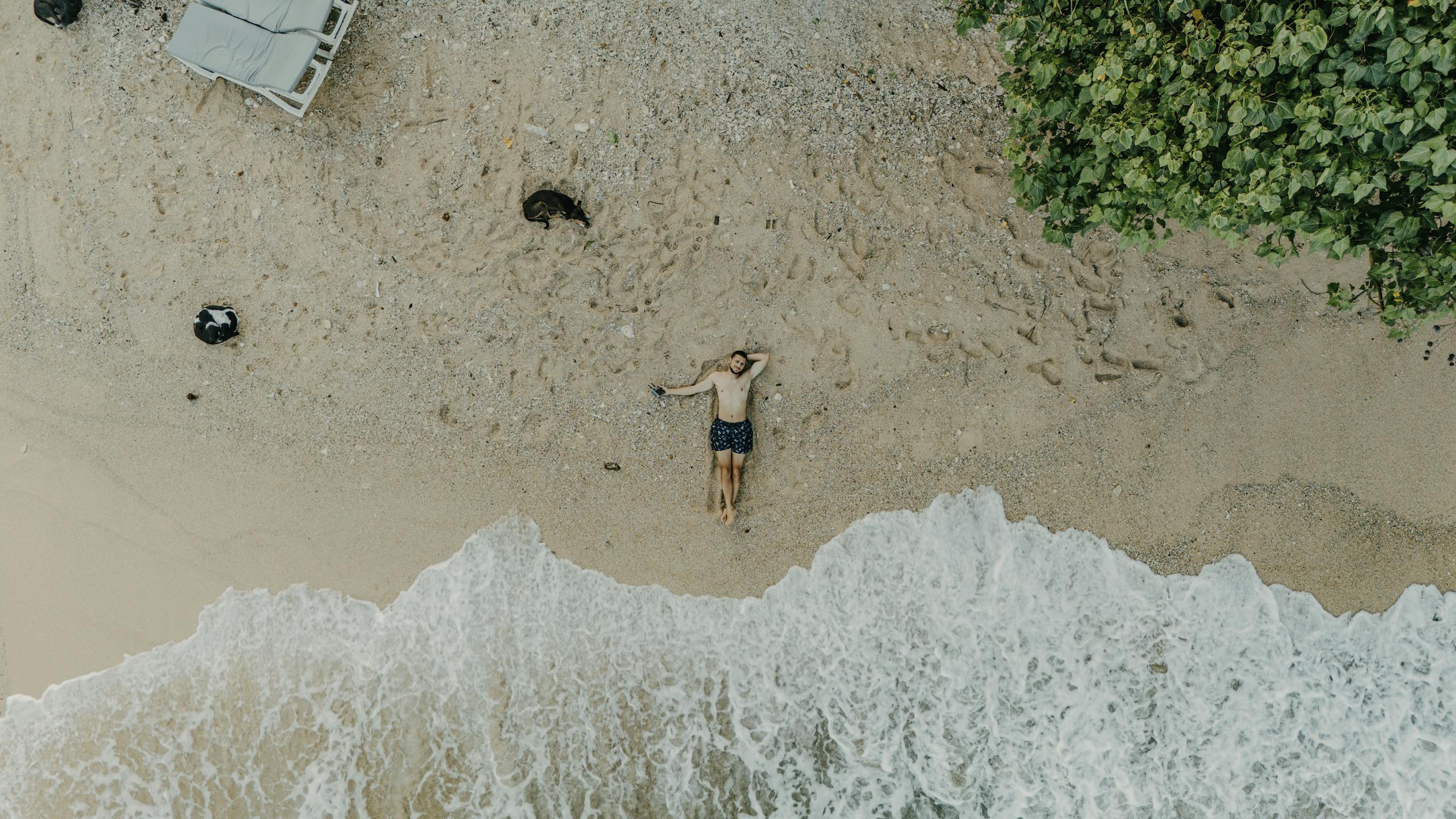A tranquil aerial shot captures a person resting on a sandy beach by the ocean in Sri Lanka.