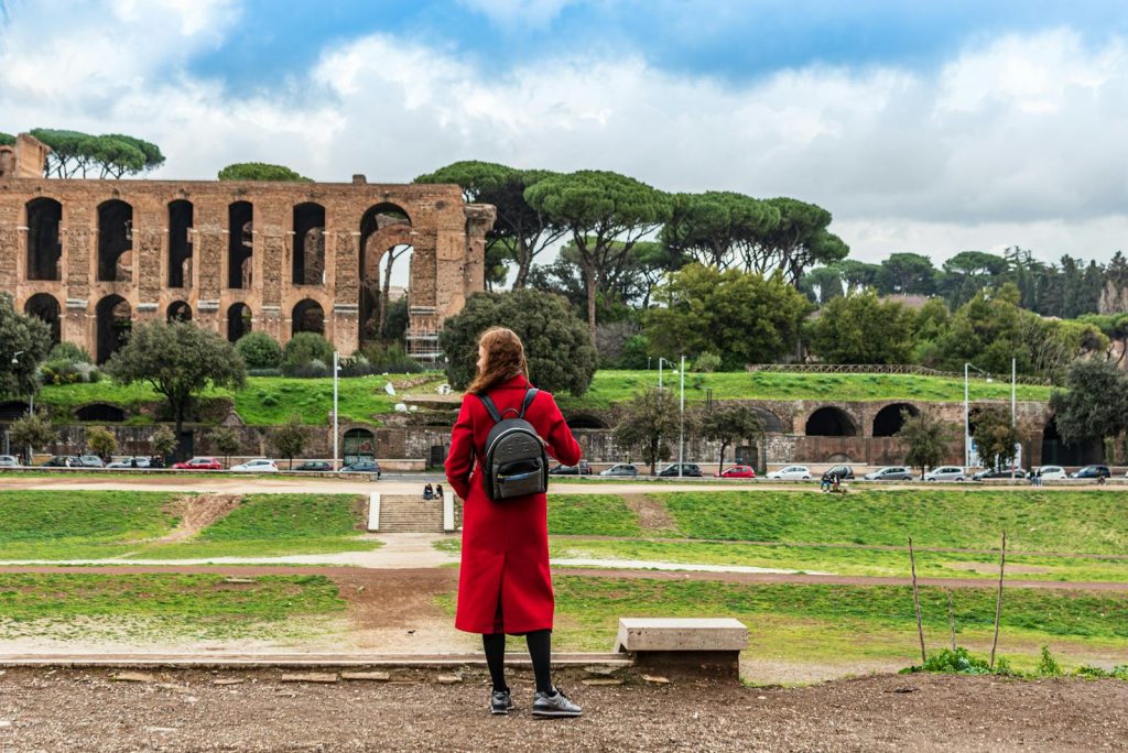 Woman in red coat viewing the historic Circus Maximus ruins in Rome, Italy.