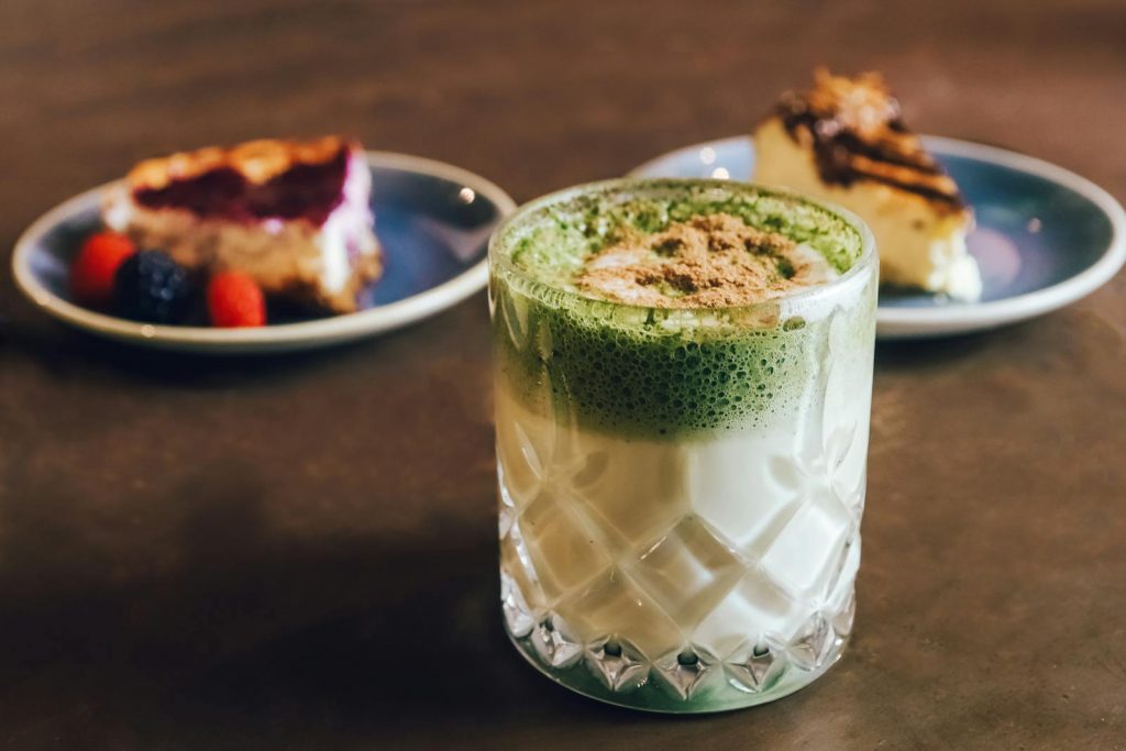 Close-up of creamy matcha latte with pastries on a stylish table setting.