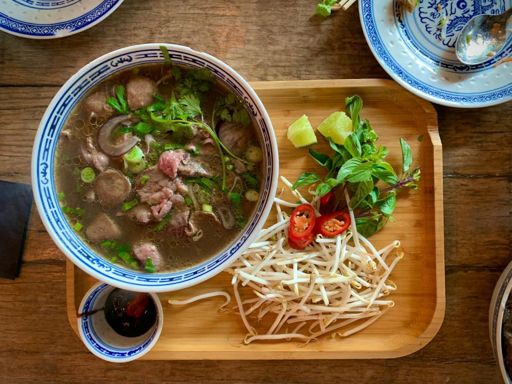 Enjoy this vibrant Vietnamese pho served with fresh herbs and spices on a wooden tray.