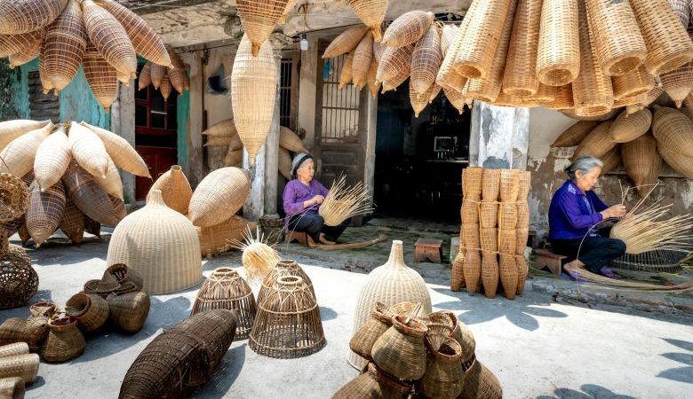 Elderly Vietnamese women creating bamboo baskets in a rustic rural setting.