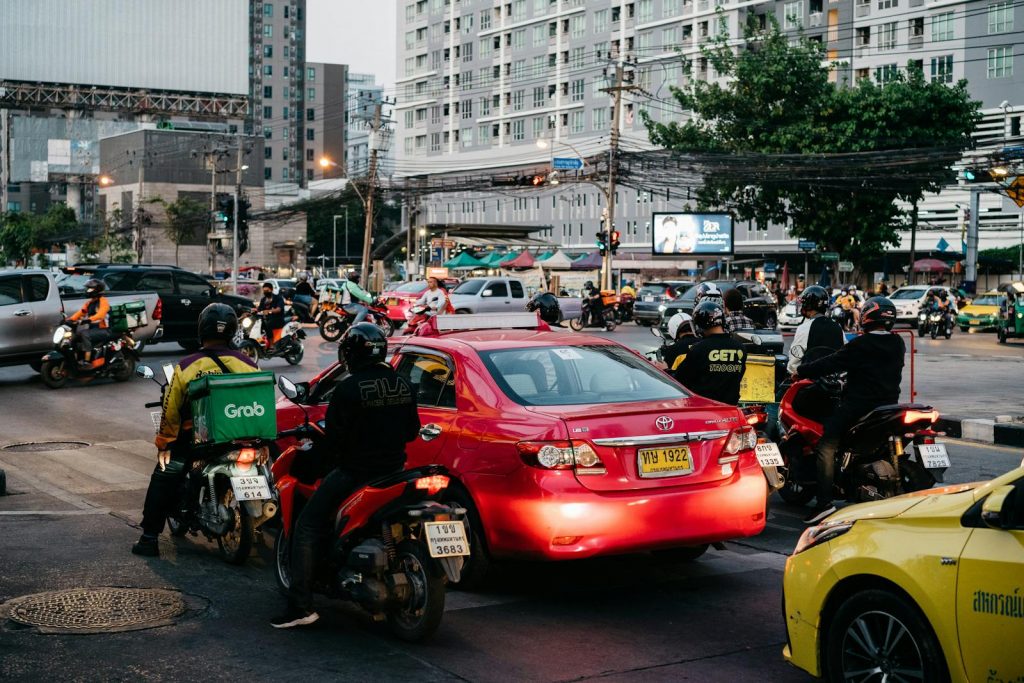 Busy traffic at a Bangkok intersection with cars and motorbikes during rush hour.