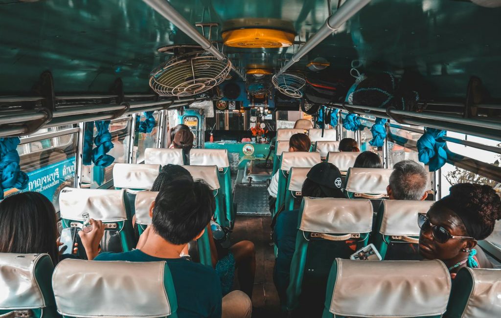A diverse group of tourists traveling on a bus in Kanchanaburi, Thailand.