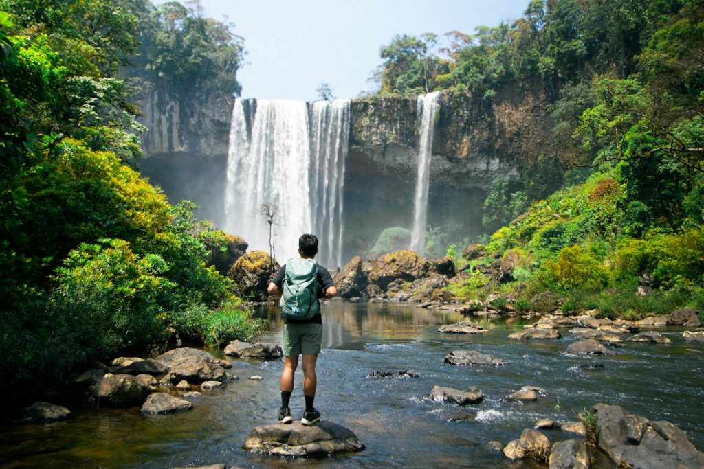 Adventurous hiker enjoying a mesmerizing waterfall in Kon Tum, Vietnam.