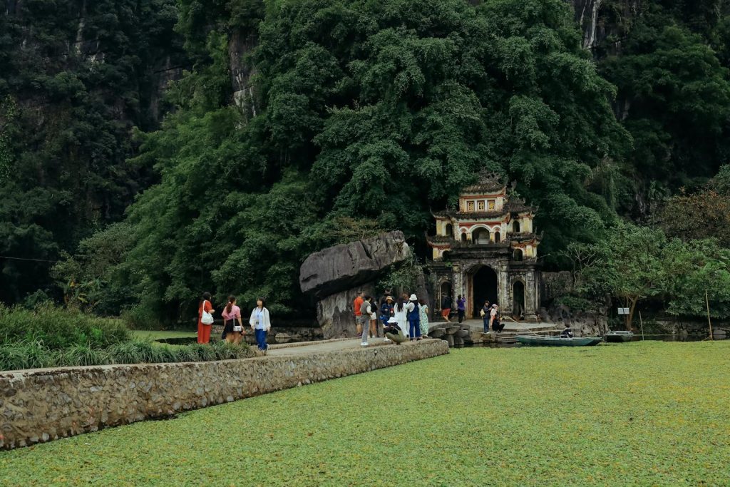 Travelers exploring the historic Bích Động Pagoda surrounded by lush greenery in Ninh Bình, Vietnam.