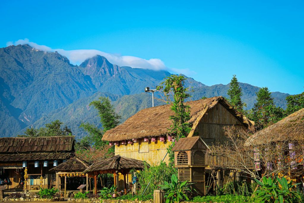 Scenic view of traditional thatched houses with mountains in Sapa, Vietnam.