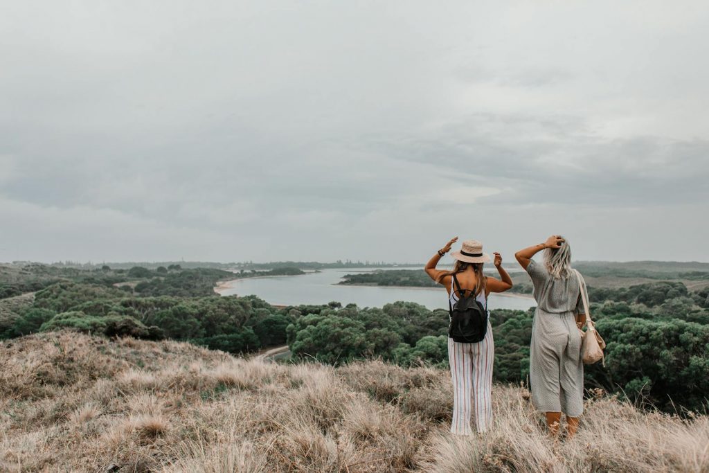 Two women overlooking a stunning natural landscape with a river and lush greenery.