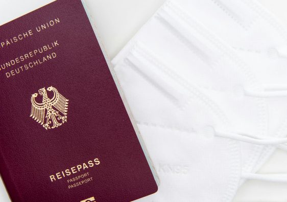 Close-up of a German passport and KN95 masks symbolizing travel during the pandemic.