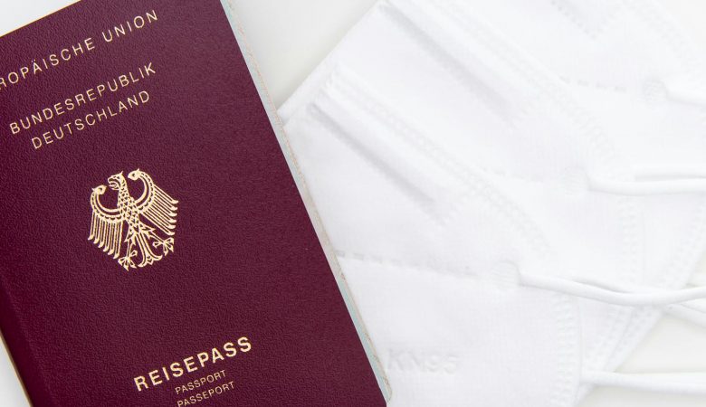 Close-up of a German passport and KN95 masks symbolizing travel during the pandemic.