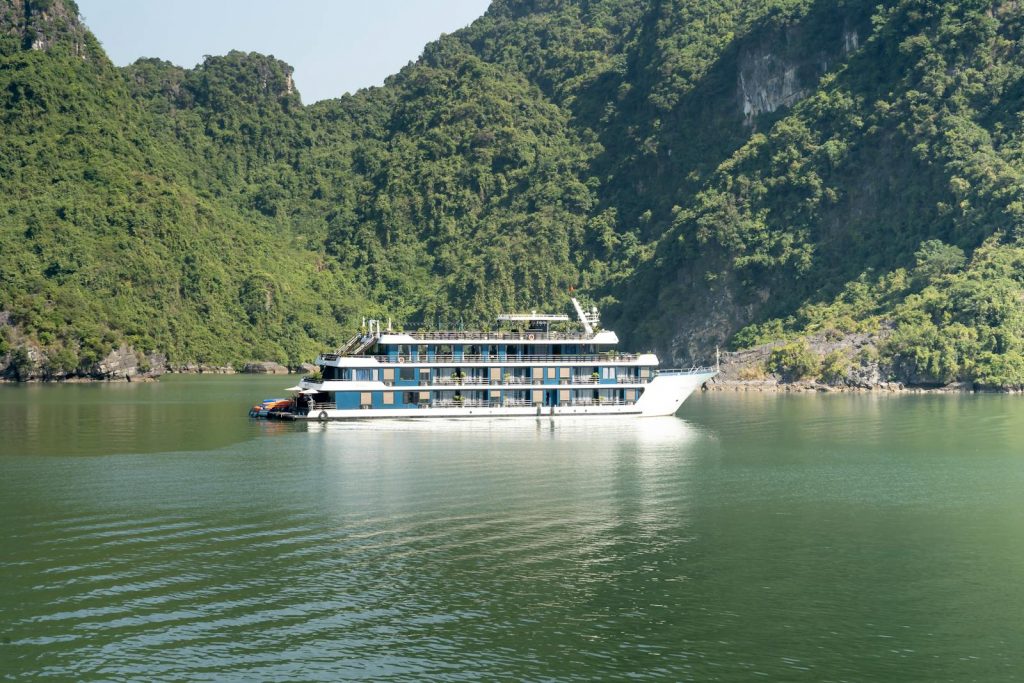 A tranquil scene of a ferry cruising through Halong Bay surrounded by lush green hills.