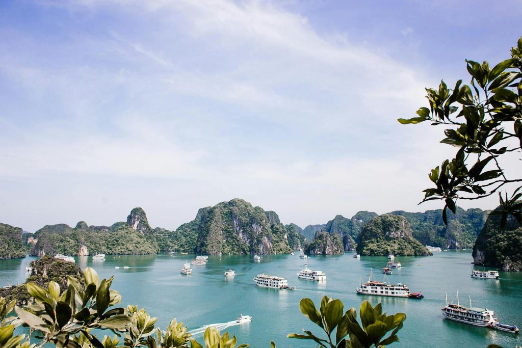 Serene Halong Bay vista featuring iconic limestone islands and boats under a clear sky.
