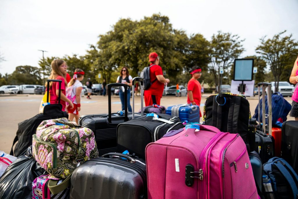 Group of travelers with colorful luggage at outdoor parking area.