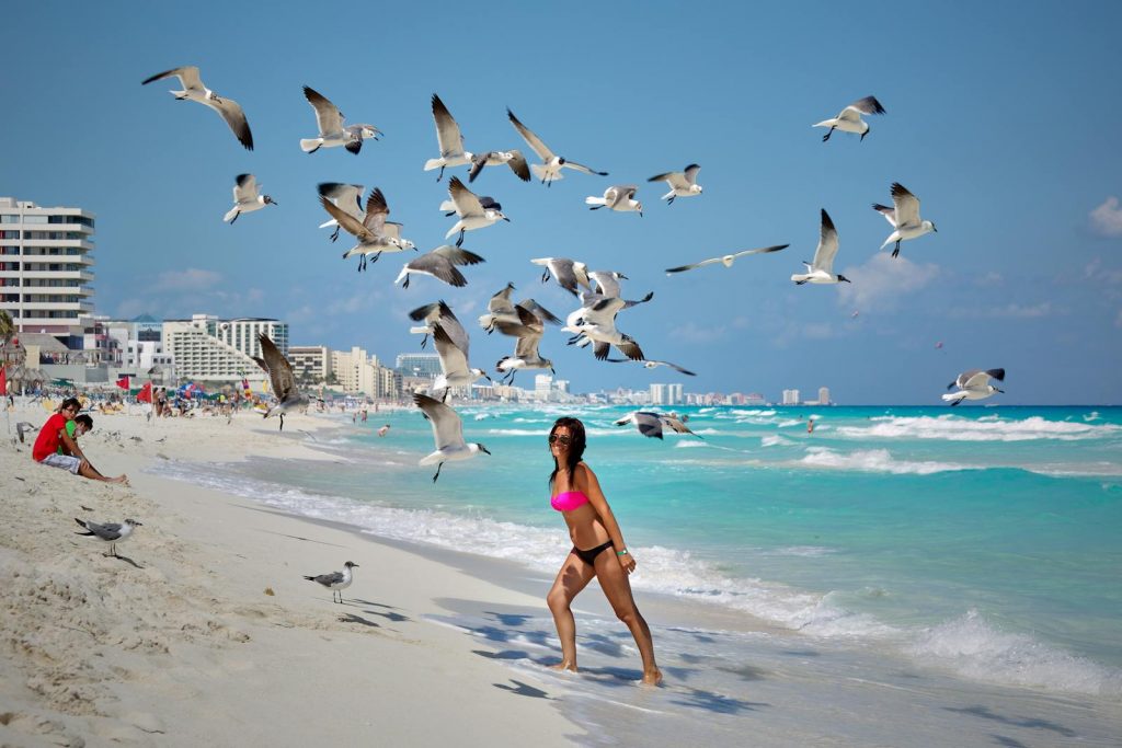 Woman on Cancun beach enjoying the summer surrounded by seagulls.