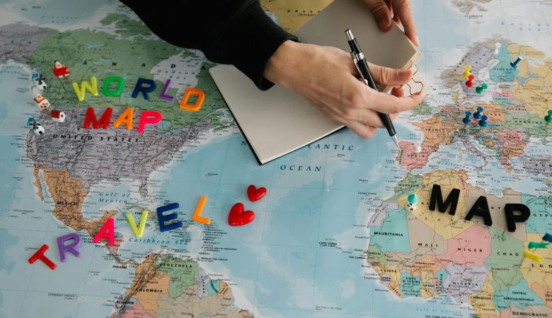 Hands holding pen and notebook over vibrant world map planning a journey.