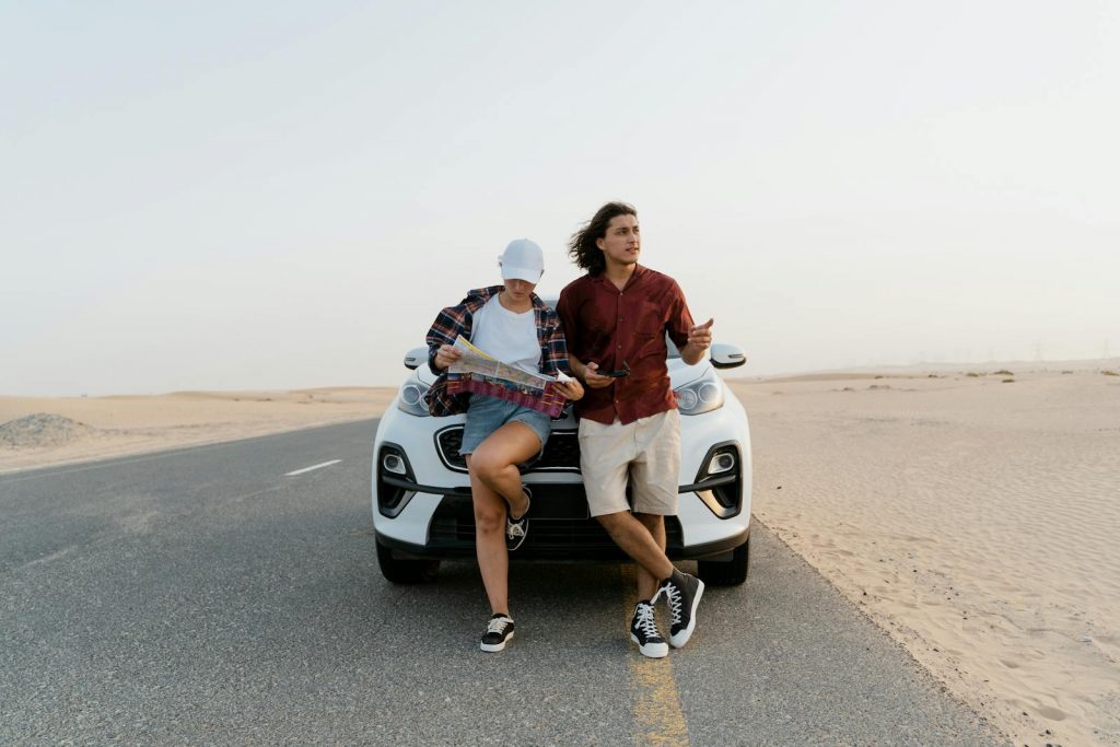A couple reviews a map while standing next to their car in a desert. Perfect for travel and adventure themes.