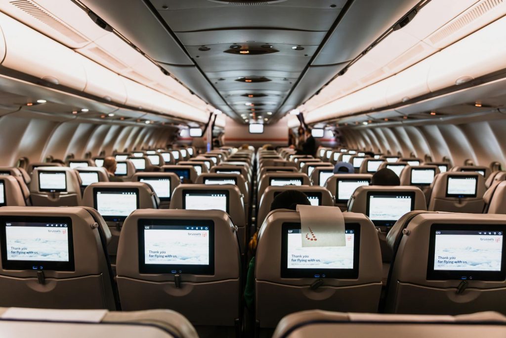 Comfortable airplane cabin interior featuring in-flight entertainment screens on all seats.