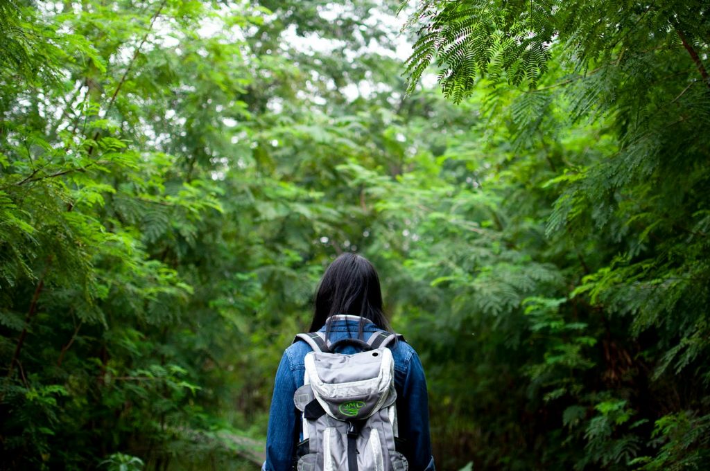 A young woman explores a lush forest trail in Guangzhou, China, embracing nature and adventure.