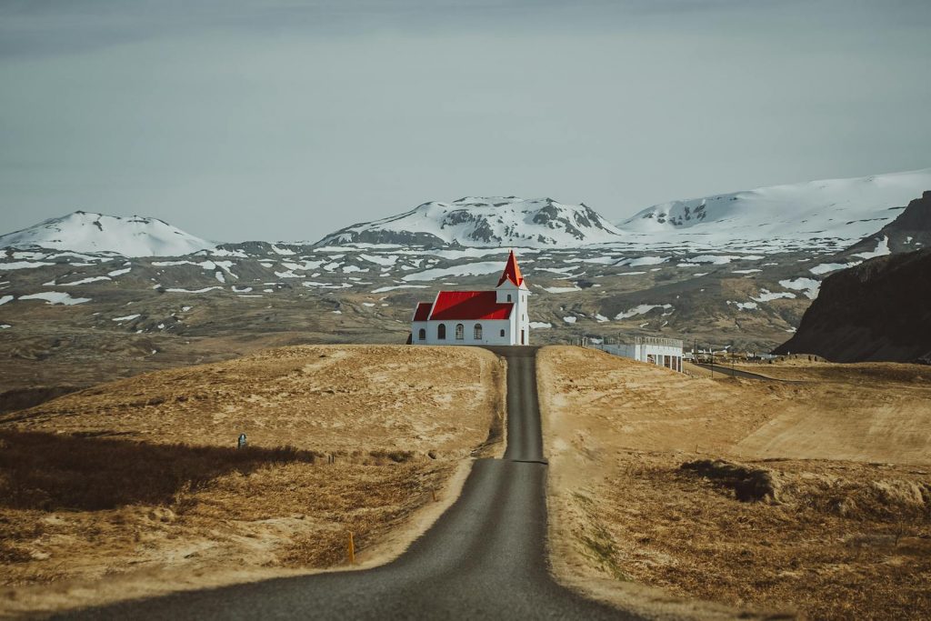A stunning view of Ingjaldshóll Church with snowy mountains in Iceland's arid landscape.