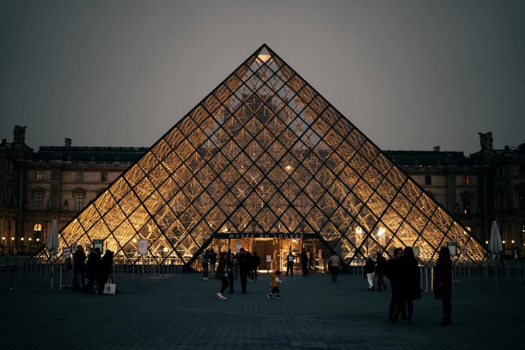 Beautiful view of the Louvre Pyramid lit up at twilight in Paris, creating a stunning architectural scene.