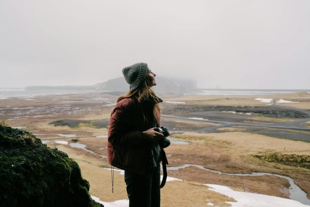 Woman with camera enjoying a cold, scenic Nordic landscape—winter photography exploration.