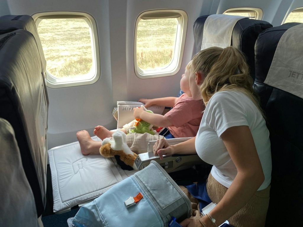Mother and child sitting inside airplane, enjoying scenic view through windows during flight travel.