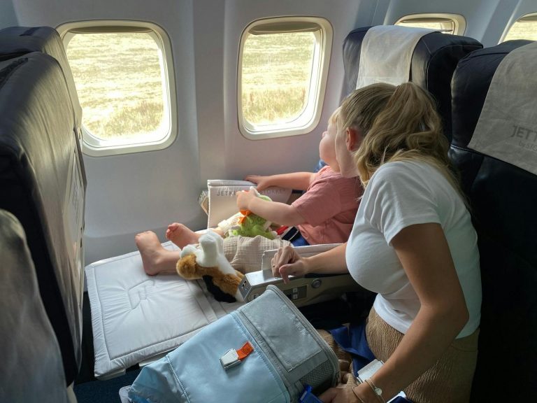 Mother and child sitting inside airplane, enjoying scenic view through windows during flight travel.