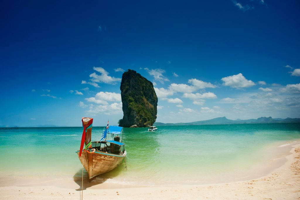 Longtailboot an einem tropischen Strand in Thailand vor Kalksteinfelsen