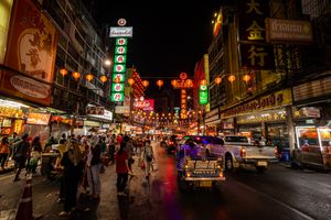 Explore the lively atmosphere of Bangkok's Chinatown illuminated by neon lights and bustling street life.
