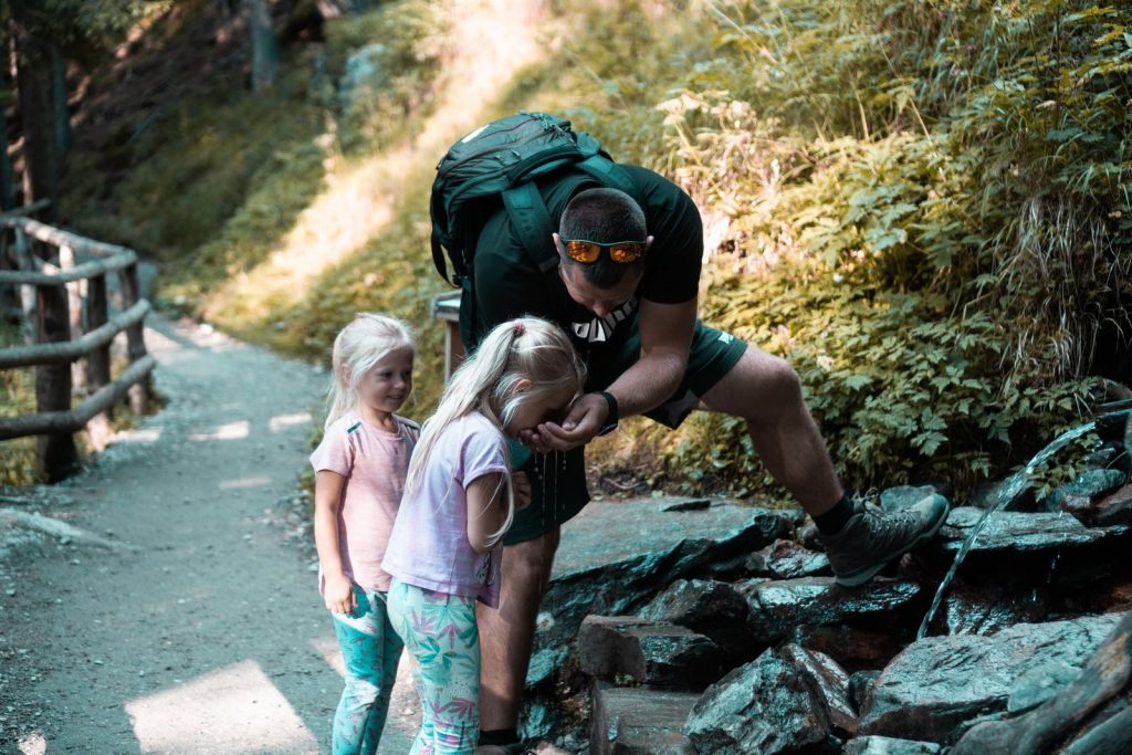 Father with daughters exploring nature on a forest path during a hike.