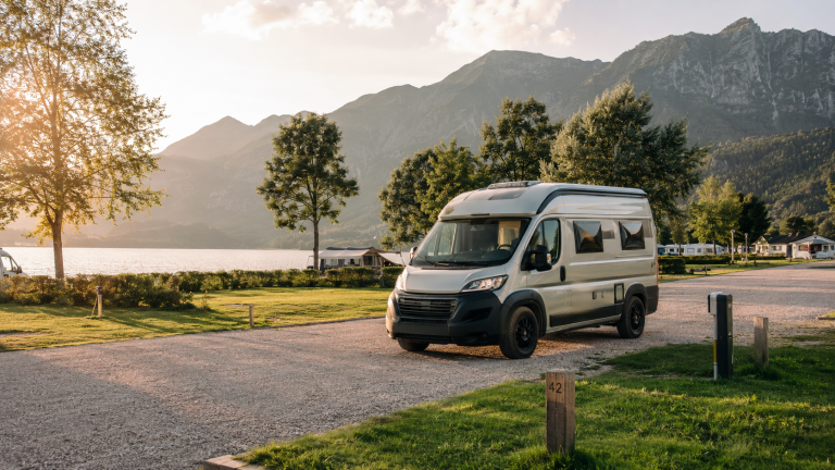 Wohnmobil auf einem Campingplatz am See mit Bergen